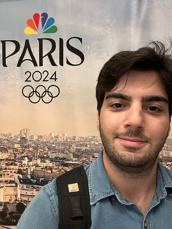 Quinnipiac Alumni posing in front of the Winter 2026 Olympics sign