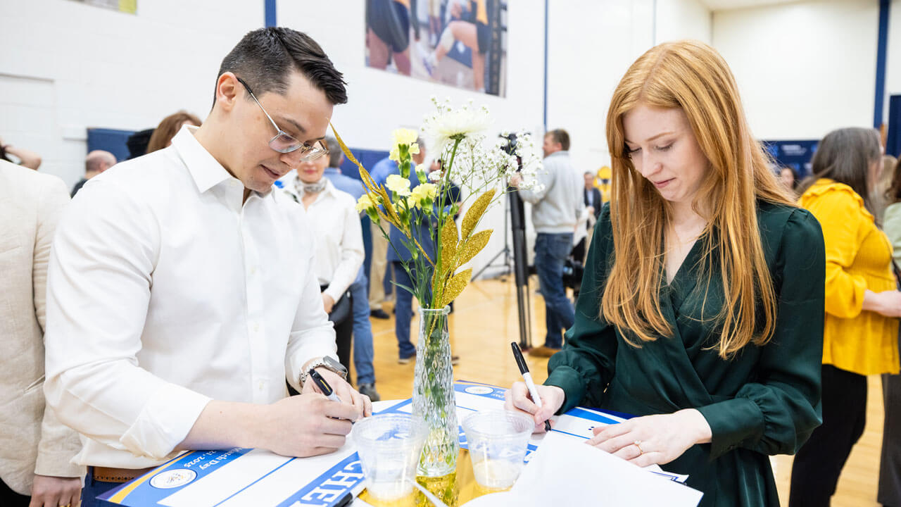 Two School of Medicine students stand at a table writing on some paper with sharpies