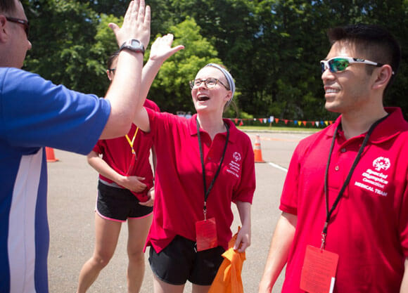 Students hi-five participants at an event at the Special Olympics summer games in New Haven