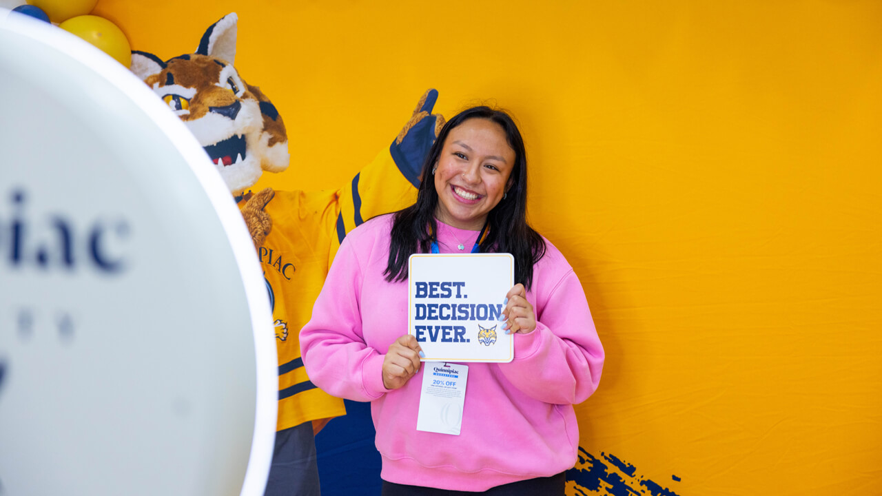 Individual poses for a photo holding a sign