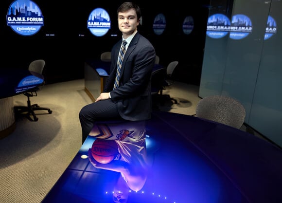 Quinn Guth sitting on a table in a suit