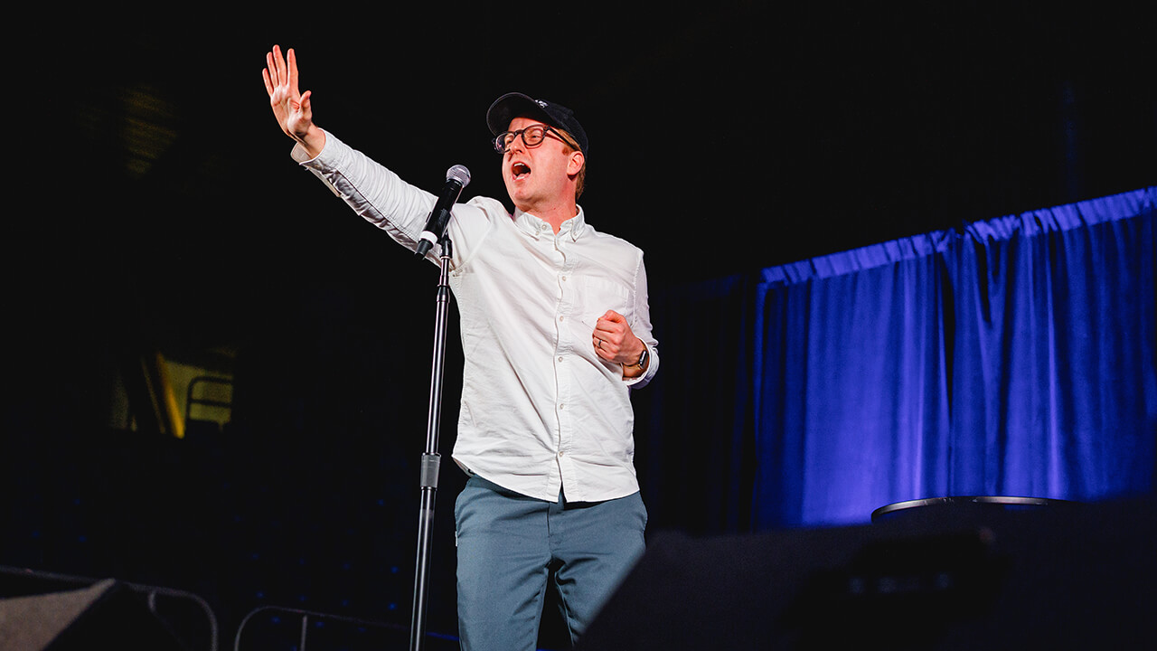 James Austin Johnson tells a joke from on stage.