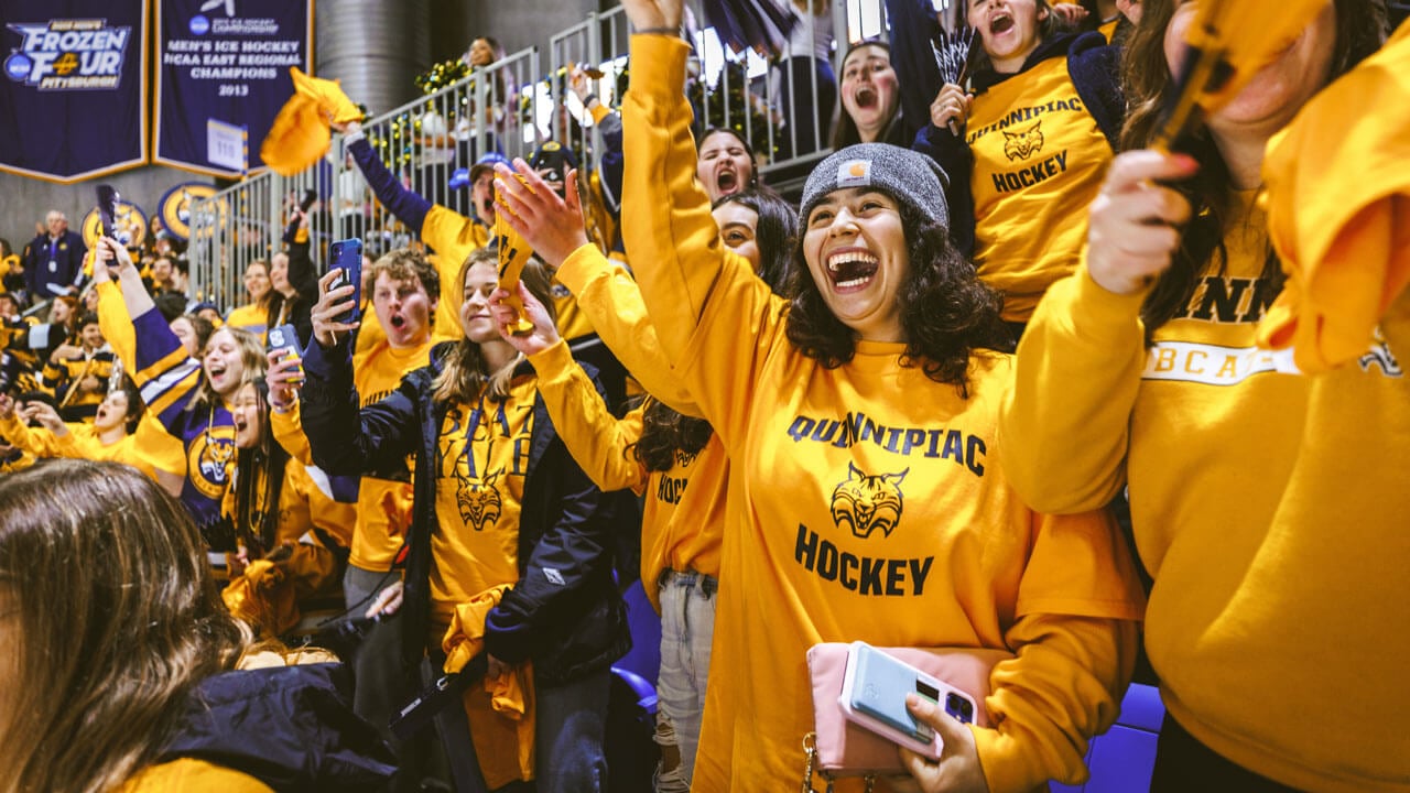 Hundreds of Quinnipiac students in Bobcat gold cheer during an ice hockey game
