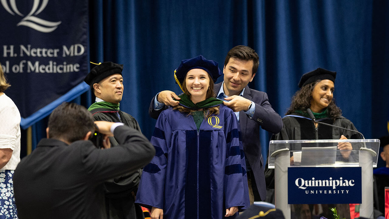 graduate receives hood from a loved one