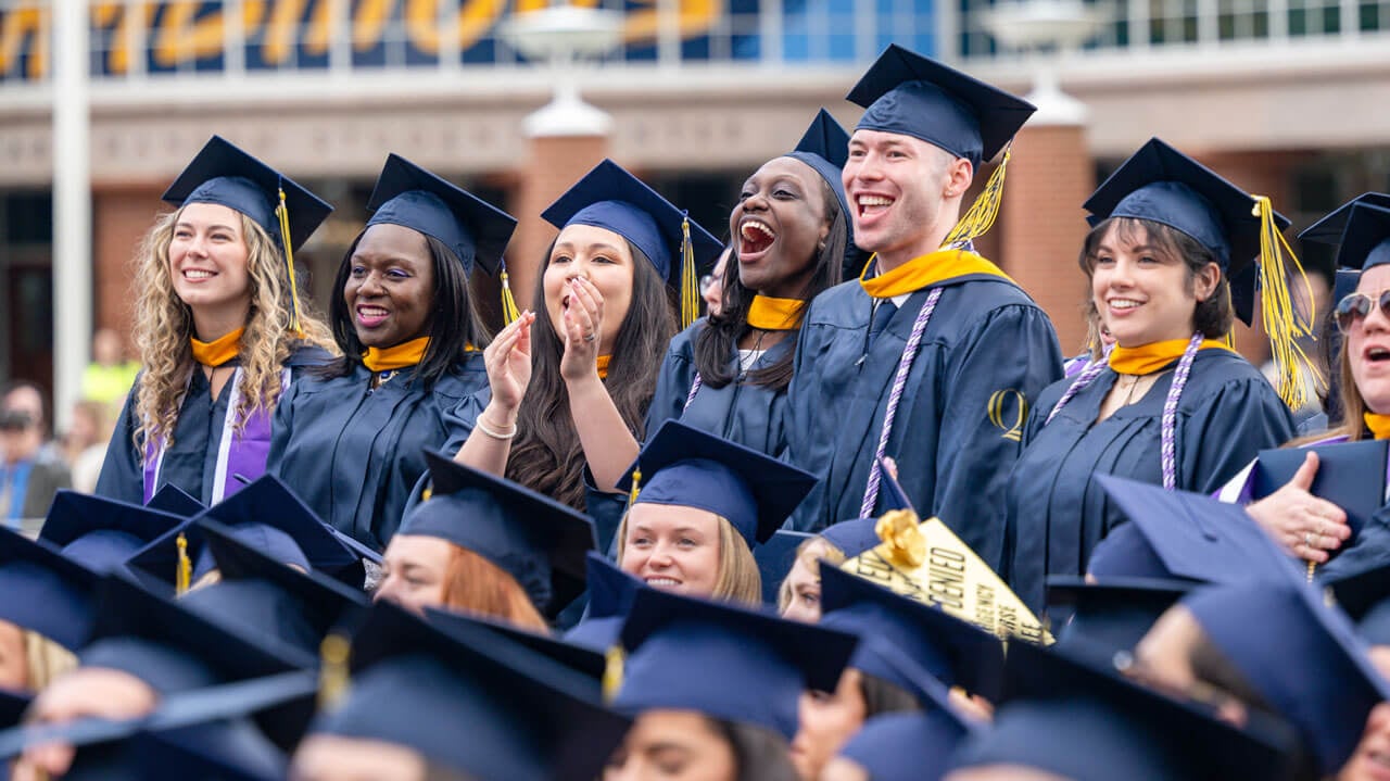 Quinnipiac graduates in the crowd stand and cheer