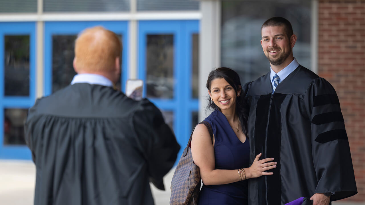 A graduate poses for a photo with one of his guests