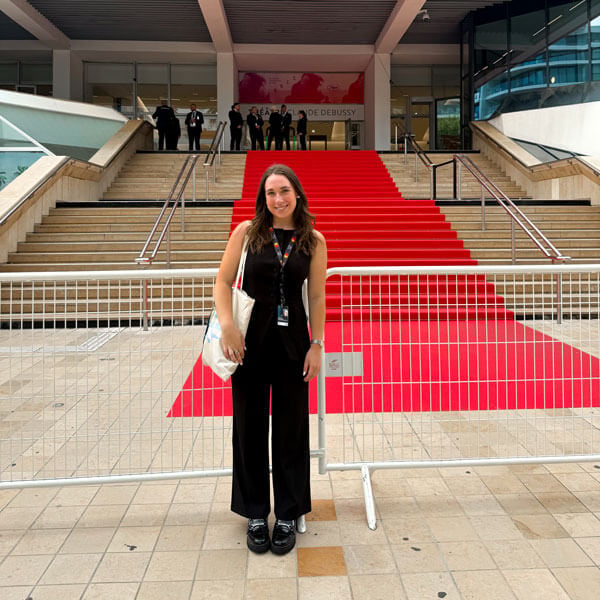 Individual stands in front of the Cannes Film Festival red carpet.