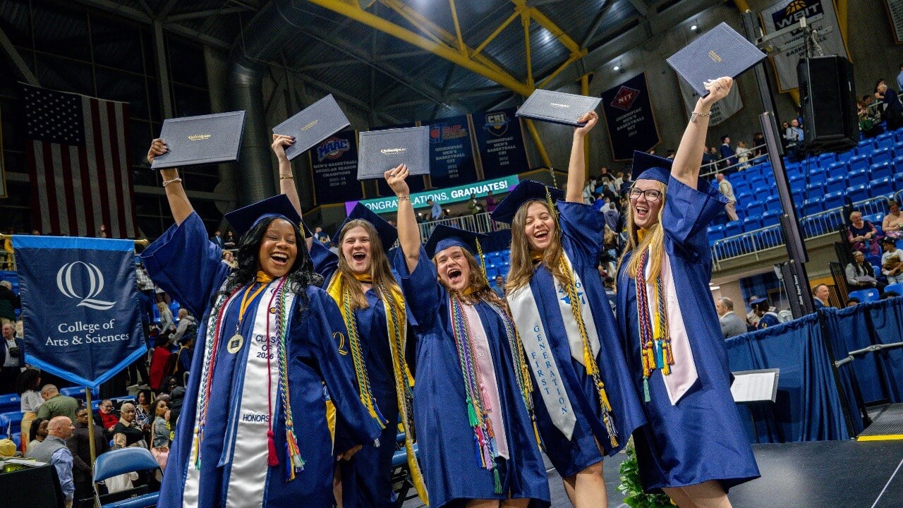 Graduates on stage holding up their diplomas