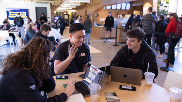 Students sitting in Recreation and Wellness Center with laptop open