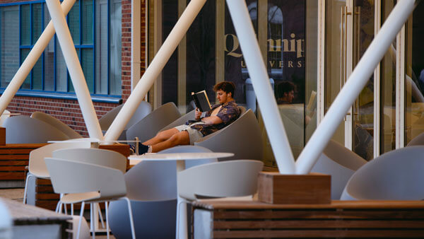 Student sitting in white chairs by Echlin and Admissions Office