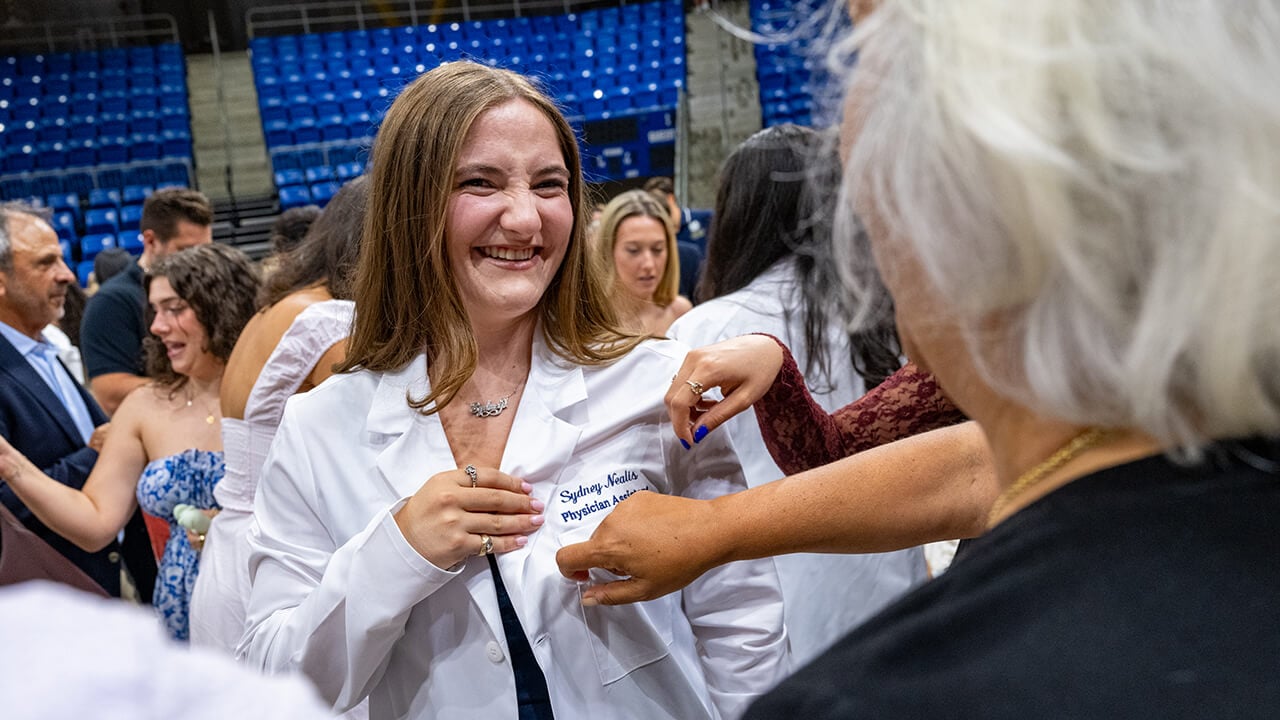 Student showing her white coat to family