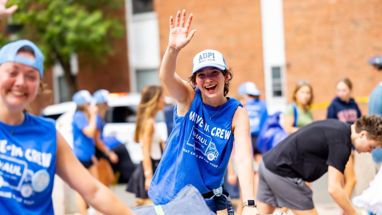 Move-in crew member waves while pushing a cart