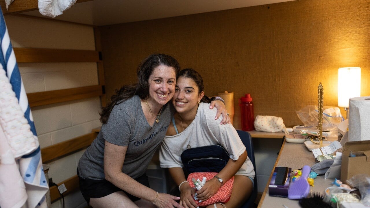 Parent and new student smile in residence hall room