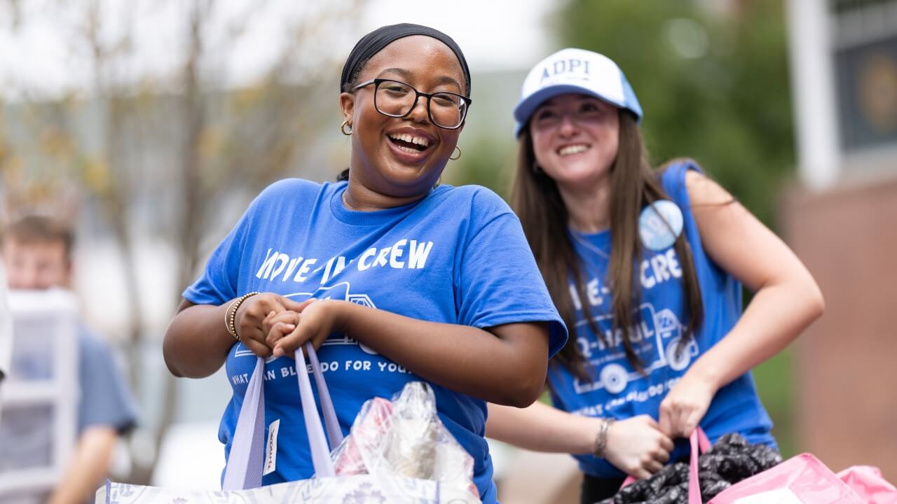 Move-in crew members smile while holding bags