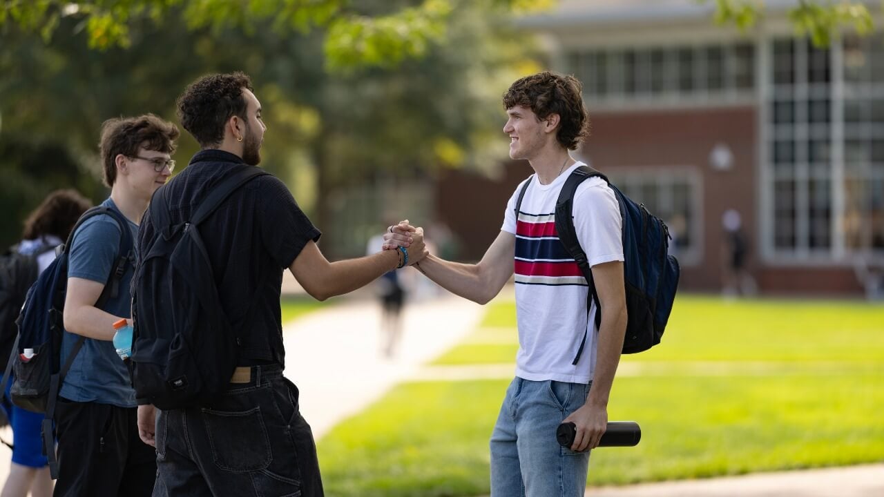 Two students greet each other with a handshake