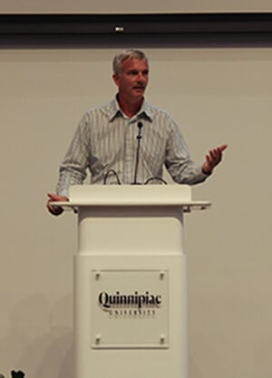 Jason Burke standing at the Quinnipiac podium