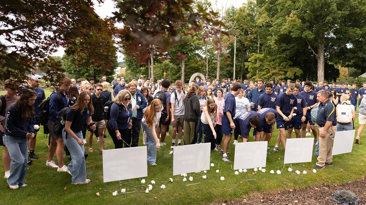 Students, faculty, staff and community members placing flowers in front of the signs of the 9/11 victims.