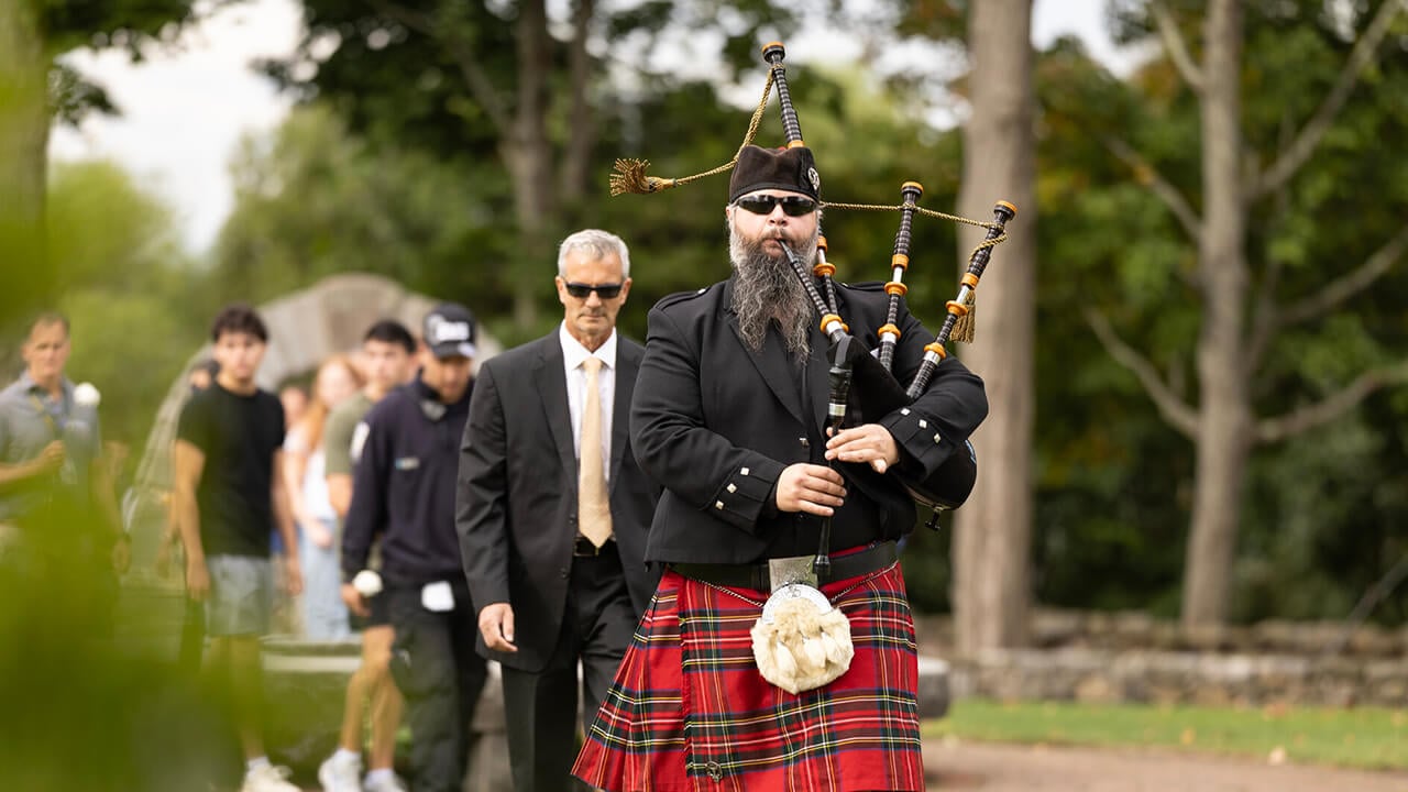 Bagpiper leading procession into the alumni gardens