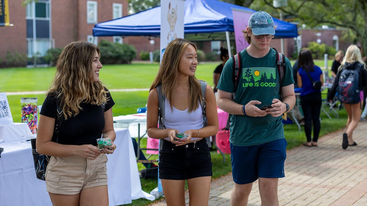 Three students walking through the local business showcase