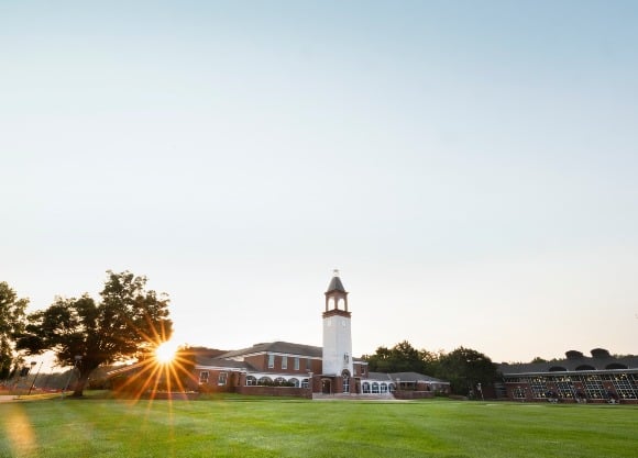 The sun comes up behind the library on the Quinnipiac Quad