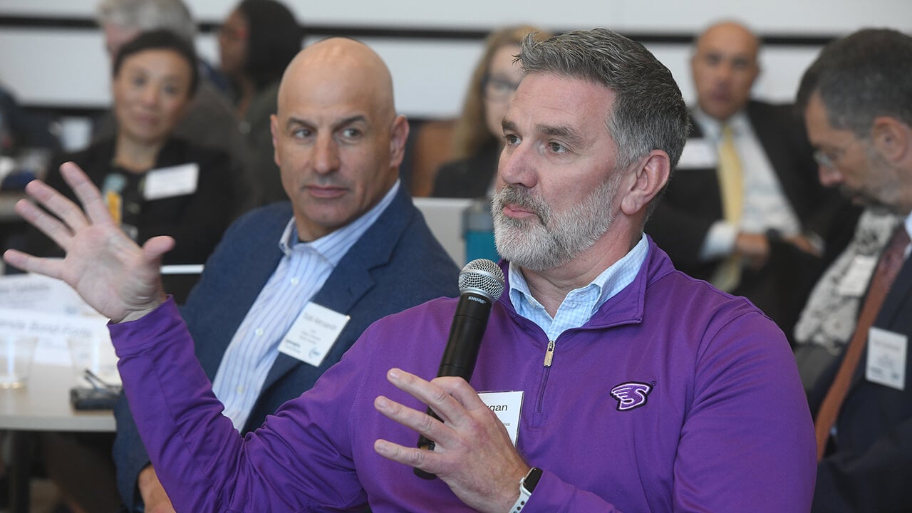 Person in purple sweater speaking into microphone