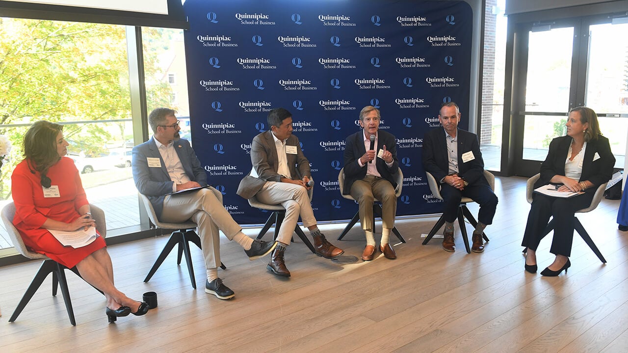 Group of individuals sit in semi-circle and speak at conference