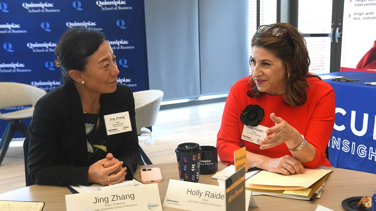 Jing Zhang and Holly Raider have a conversation at a table