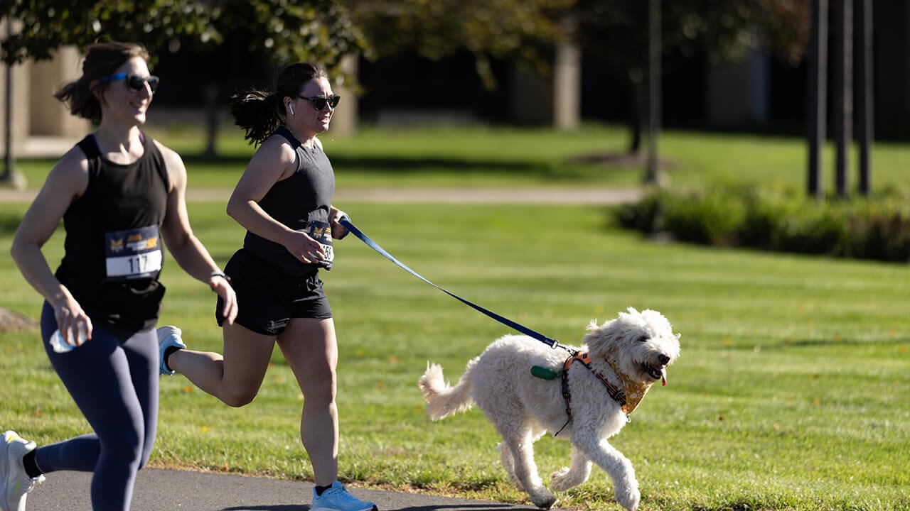 People running with a dog.