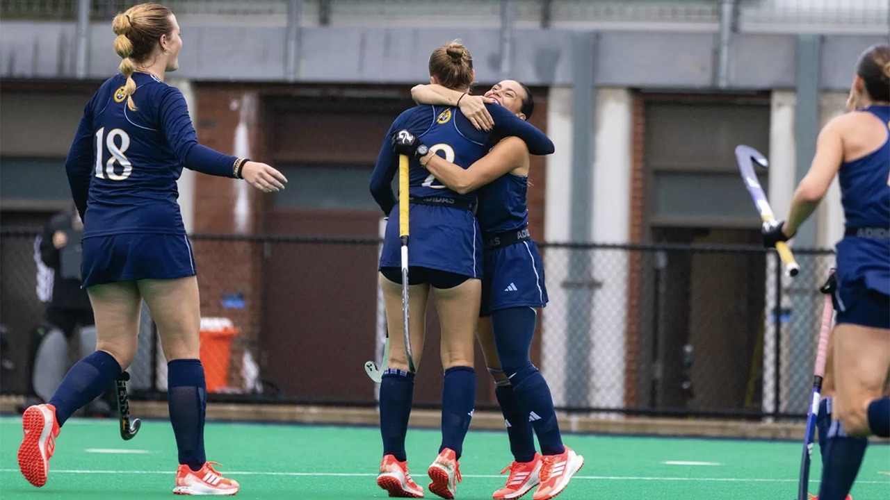 Field hockey players hug.