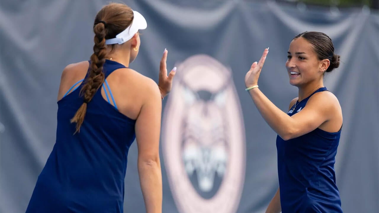 Two tennis players high-five on the court.