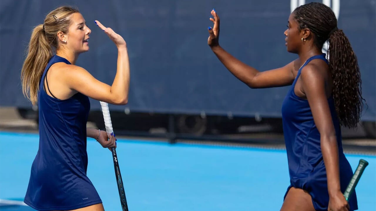 Two tennis players high-five on the court.