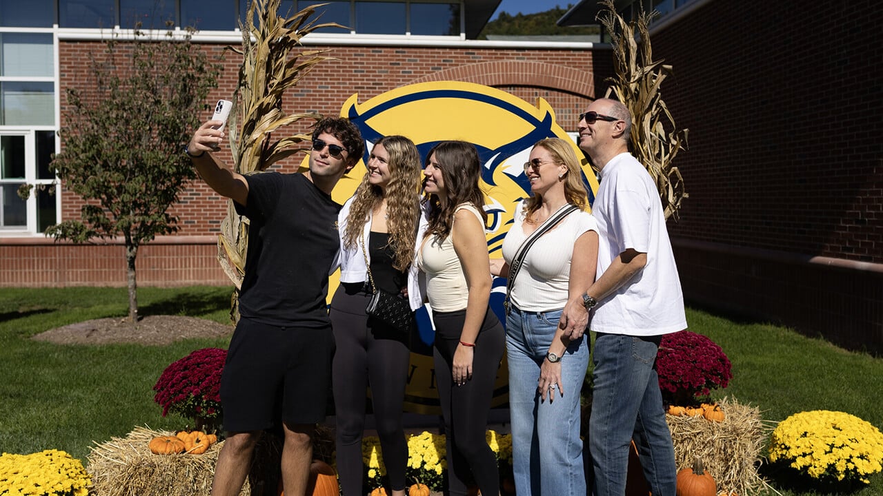 Family taking selfie with Quinnipiac logo.
