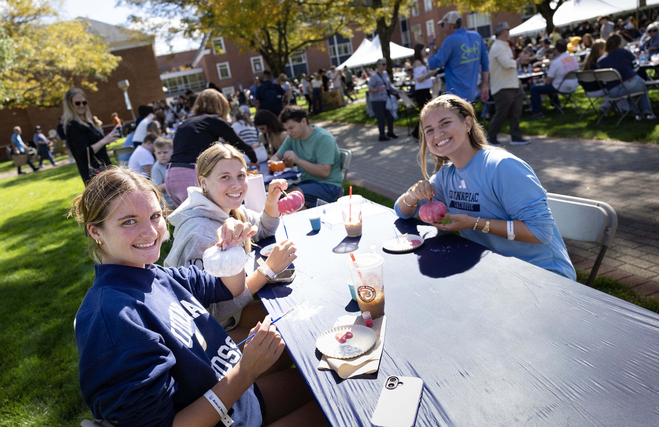 Three students holding up painted pumpkins.