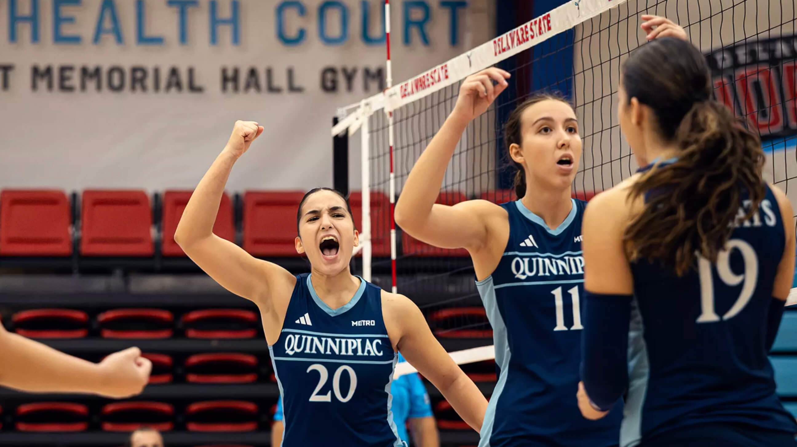 Women's volleyball players cheering with fist in the air.