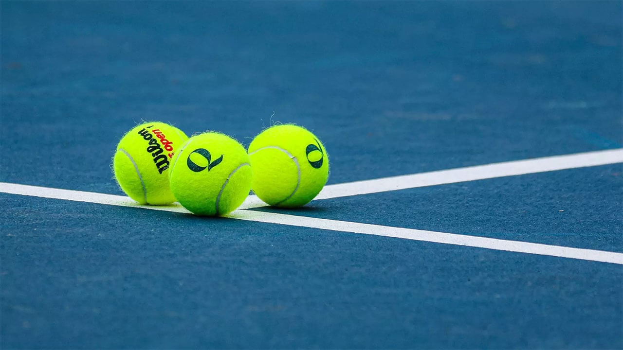 Close up of tennis balls labeled with Quinnipiac Q on the tennis court
