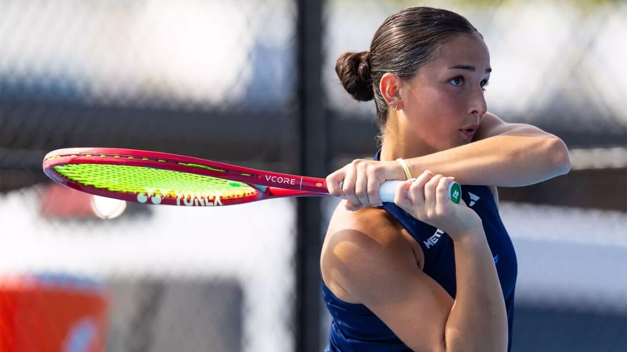 Close up of a member of the Women's Tennis team swinging her tennis racket.