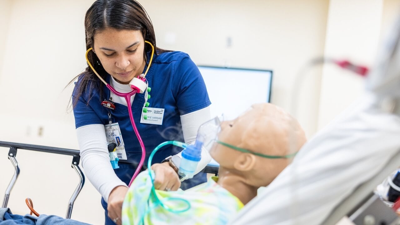 Valerie Vargas using a stethoscope on a nursing simulator.