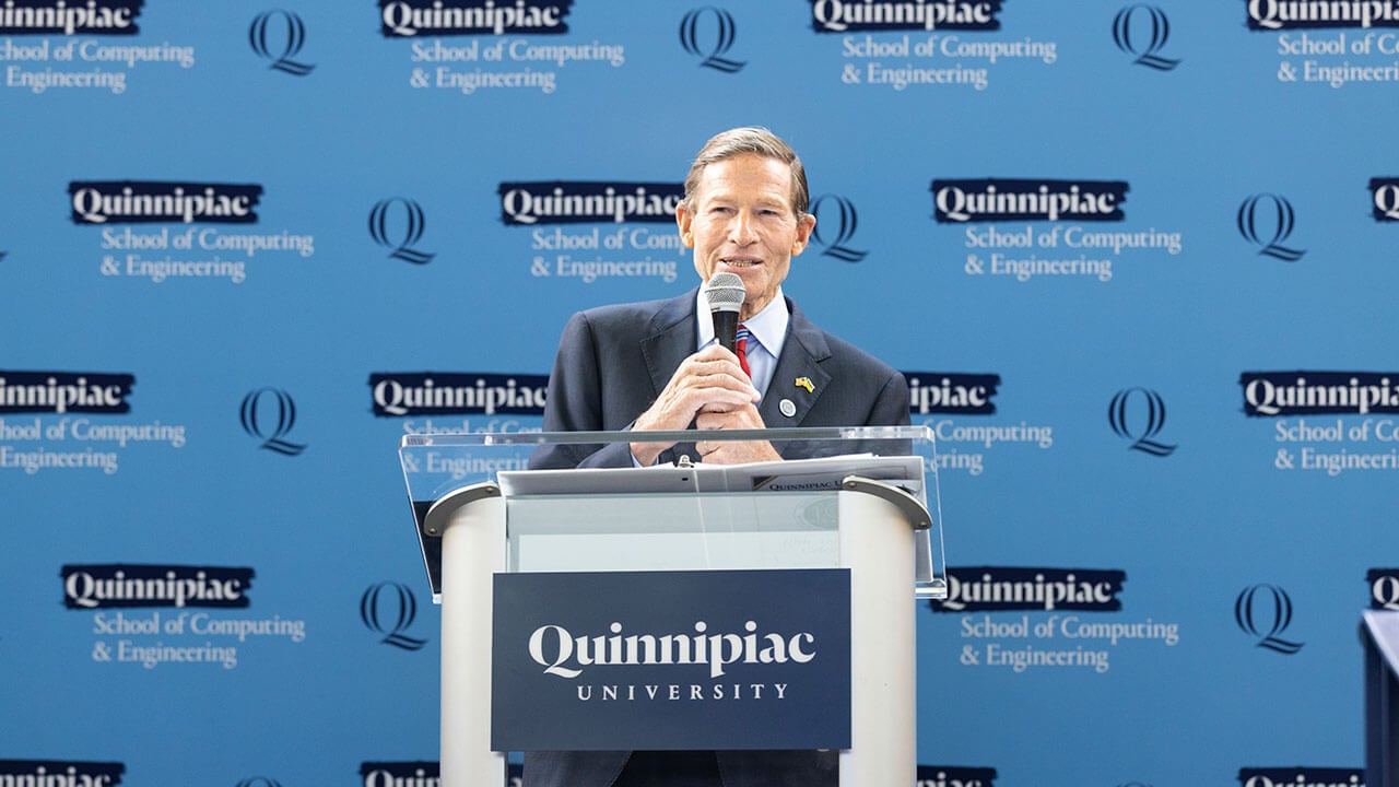 Senator Richard Blumenthal stands behind Quinnipiac University podium