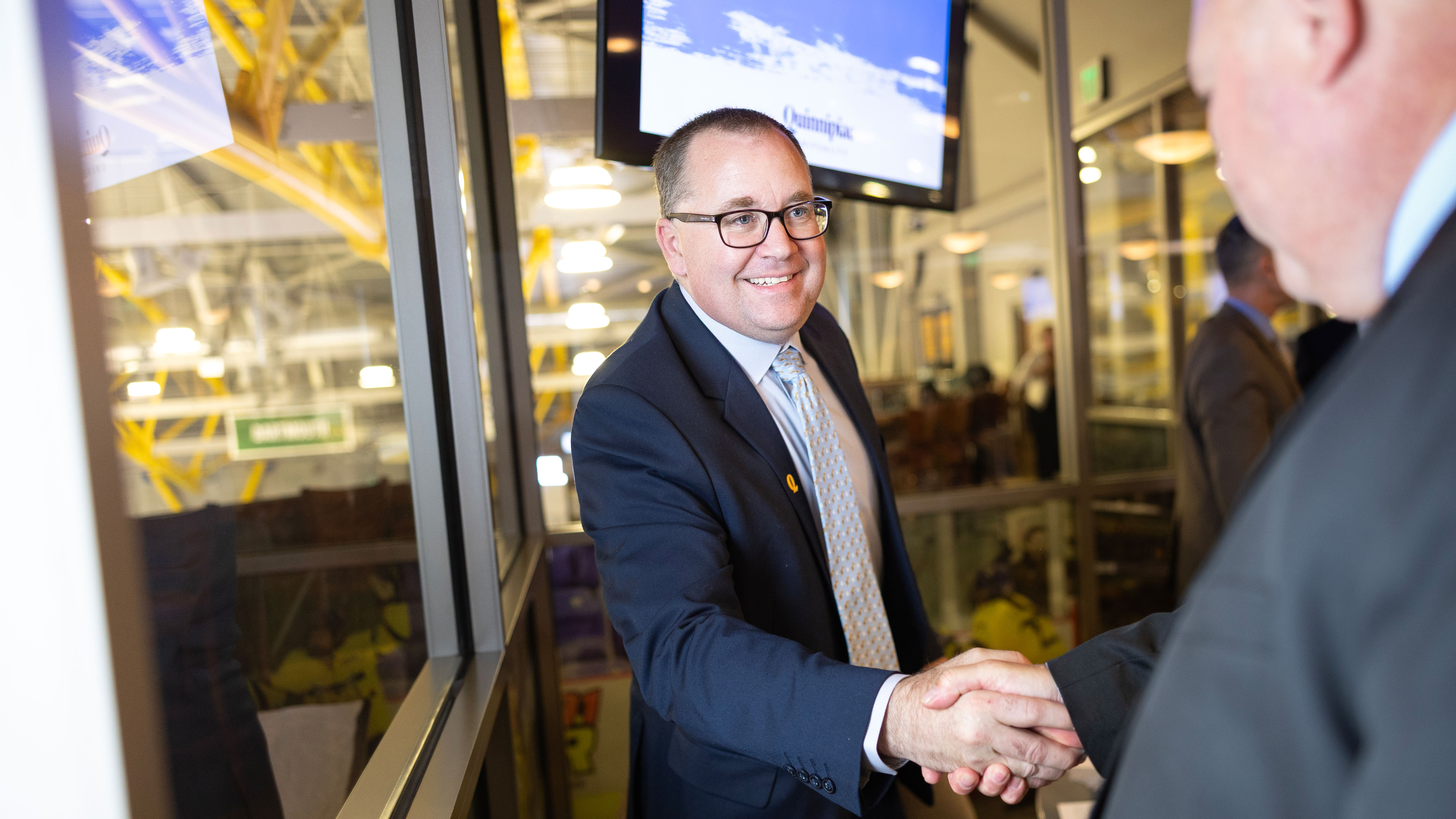 Kevin MacDougall shakes hands with someone.
