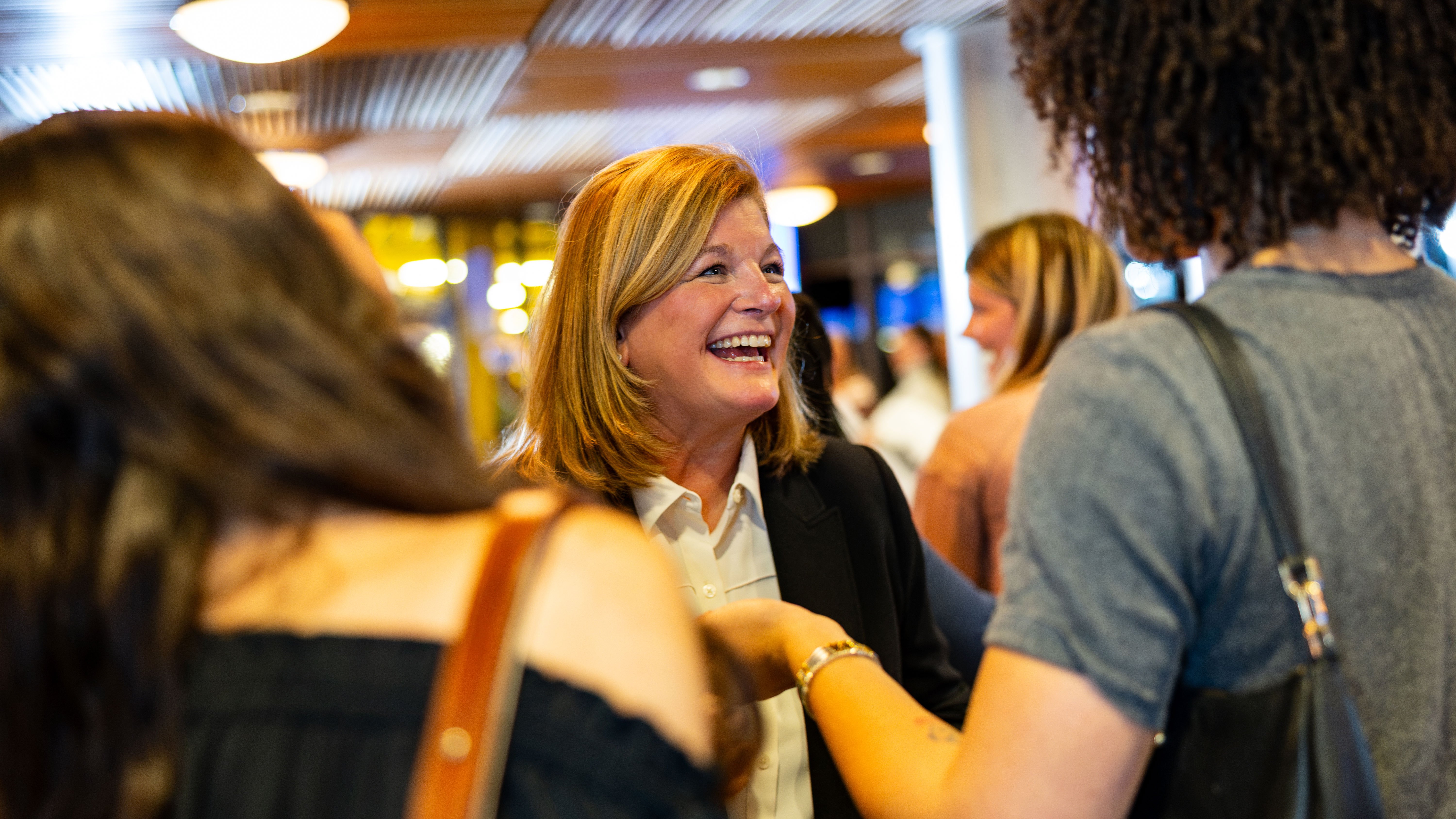 Linda Bedard smiles while talking to two people.