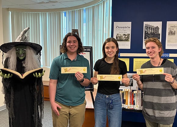 Three students holding certificates for completing the "Escape the Storybook"