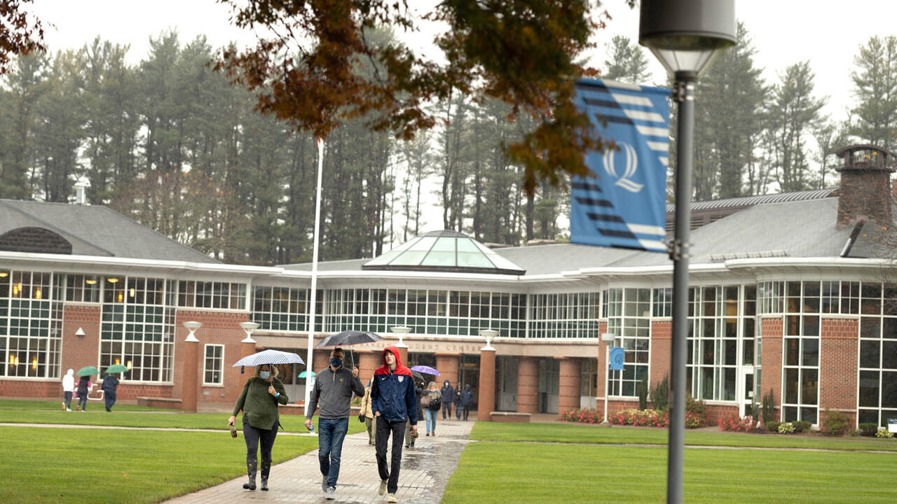 Parents and student walking in rain on the quad