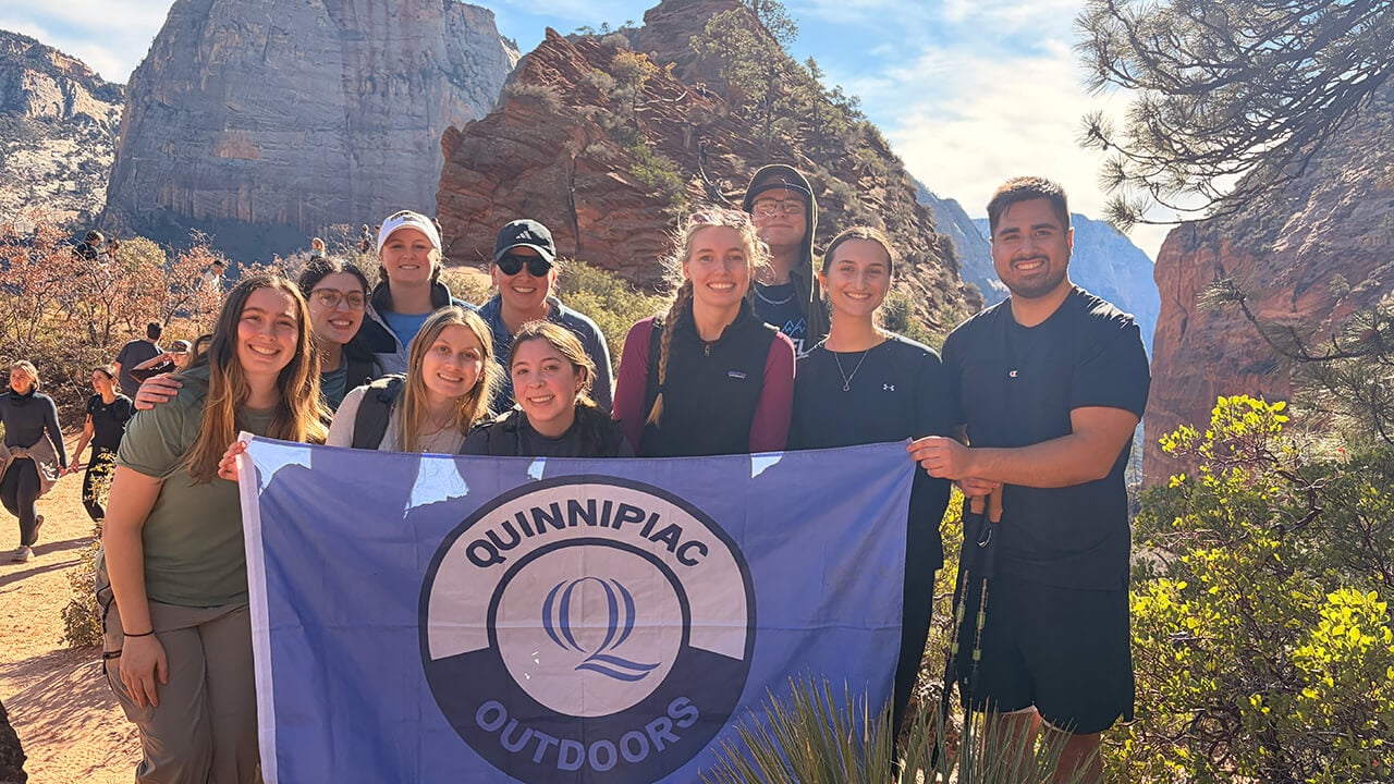 Quinnipiac students hold QU Outdoors flag