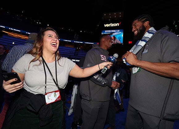 Fiske holds a mic in front of the Patriots player.